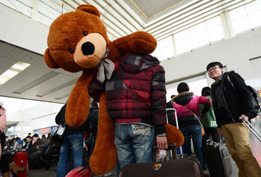 A college student carries a 1.8-meter tall toy bear through Wuchang Railway Station in Wuhan, capital of Central China's Hubei province on Jan 25, 2013. (Photo/Xinhua)