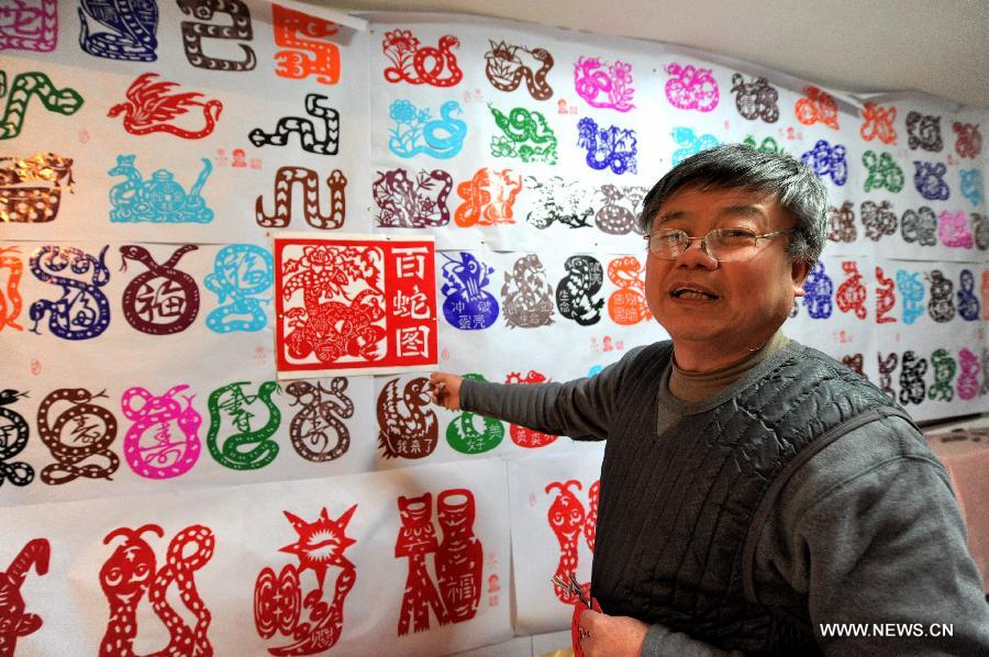 Folk artist Chen Yongnian introduces his paper-cut works in Xuzhou, east China's Jiangsu Province, Feb. 4, 2013. Chen spent over a month on creating more than 130 pieces of paper-cut artworks of snakes to celebrate the coming Chinese Year of the Snake. (Xinhua/Li Ming)