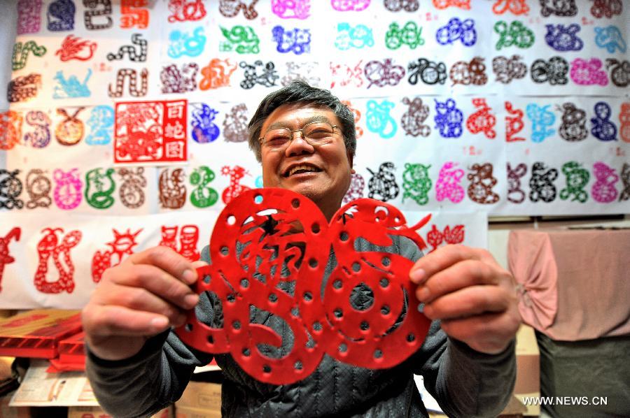 Folk artist Chen Yongnian presents his paper-cut of snake in Xuzhou, east China's Jiangsu Province, Feb. 4, 2013. Chen spent over a month on creating more than 130 pieces of paper-cut artworks of snakes to celebrate the coming Chinese Year of the Snake. (Xinhua/Li Ming)