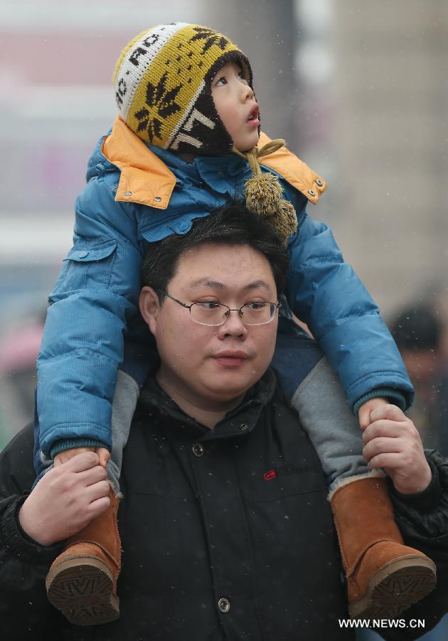 A child sitting on the father's shoulders looks at snow at the Beijing train station in Beijing, capital of China, Feb. 3, 2013. Many children travel with their families during the 40-day Spring Festival travel rush which started on Jan. 26. The Spring Festival, which falls on Feb. 10 this year, is traditionally the most important holiday of the Chinese people. Public transportation is expected to accommodate about 3.41 billion trips nationwide during the holiday, including 225 million trips by railways. (Photo/Xinhua)