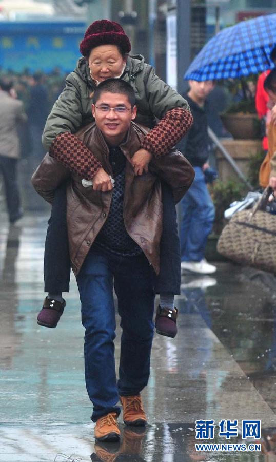 Jiang carries his mother-in-law on his back at the Railway Station of Nanning, Jan. 26.2013. (Xinhua/Huang Xiaobang)