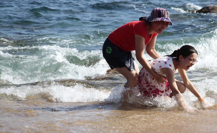 Visitors play on the seashore in Sanya, south China's Hainan Province, Feb. 5, 2013. (Xinhua/Chen Wenwu)