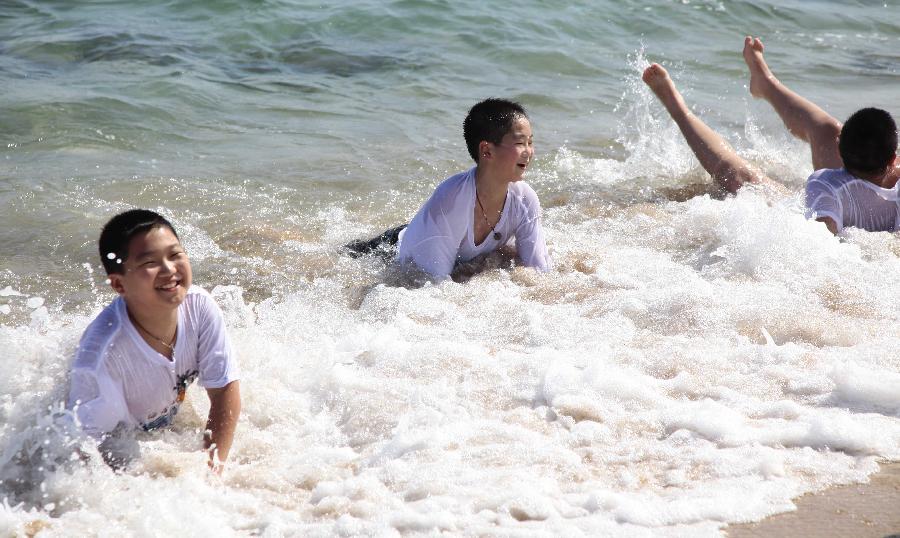 Children play on the seashore in Sanya, south China's Hainan Province, Feb. 5, 2013. (Xinhua/Chen Wenwu)