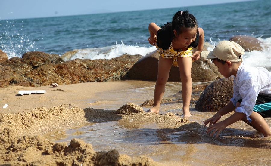 Children play on the seashore in Sanya, south China's Hainan Province, Feb. 5, 2013. (Xinhua/Chen Wenwu)