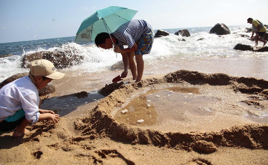 Visitors play on the seashore in Sanya, south China's Hainan Province, Feb. 5, 2013. (Xinhua/Chen Wenwu)