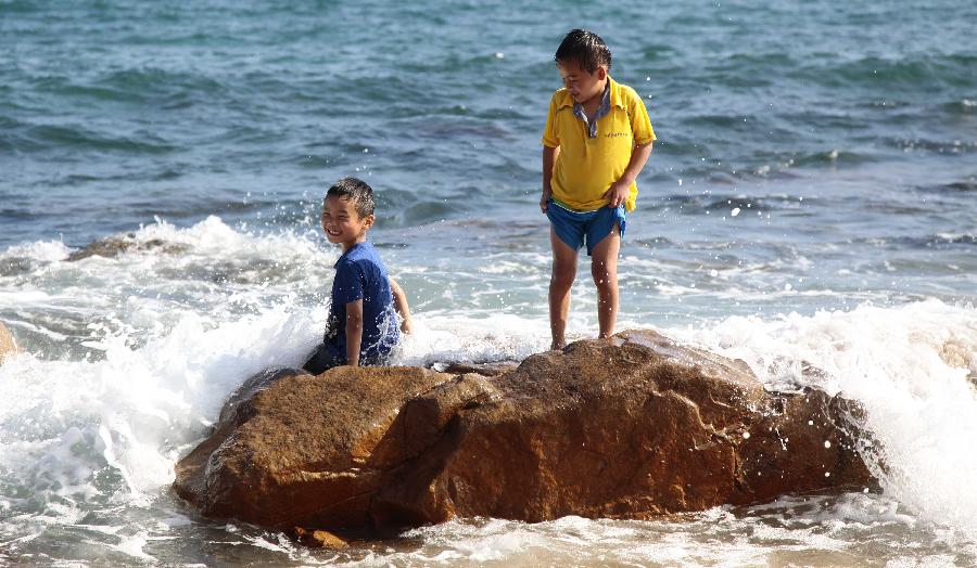 Children play on the seashore in Sanya, south China's Hainan Province, Feb. 5, 2013. (Xinhua/Chen Wenwu)