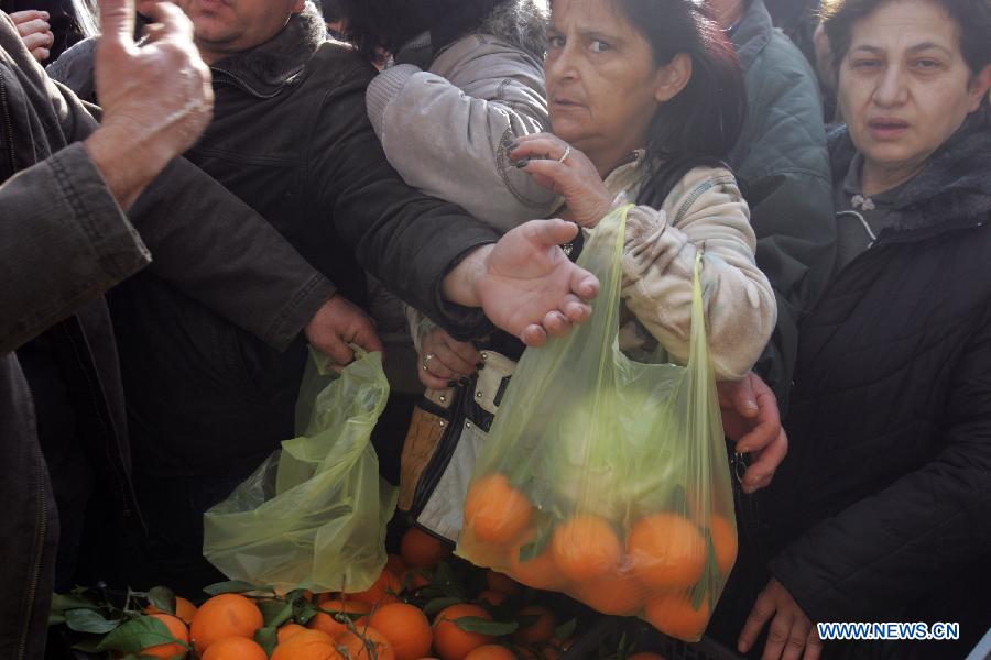 People reach out for free vegetables and fruits from farmers outside Greece's Agriculture Ministry in Athens, Greece, on Feb 6, 2013. Greek farmers continued on Wednesday their 10-day protests against tax hikes while distributing tons of vegetables and fruits for free to needy citizens. (Xinhua/Marios Lolos)