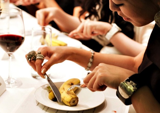 Ladies learn how to use fork and knife to cut banana. (Photo/Xinhua)