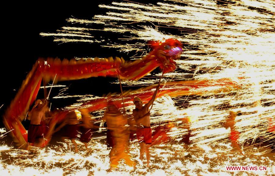 Actors perform dragon dance in firecrackers at the Daguan Park in Kunming, capital of southwest China's Yunnan Province, Feb. 6, 2013. The dance, as a derivative of traditional dragon dance in which performers hold dragon on poles and walk through floods of firecrackers, is a state intangible cultural heritage. (Xinhua/Lin Yiguang)