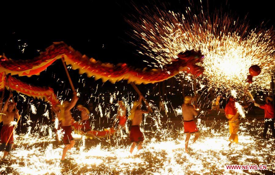 Actors perform dragon dance in firecrackers at the Daguan Park in Kunming, capital of southwest China's Yunnan Province, Feb. 6, 2013. The dance, as a derivative of traditional dragon dance in which performers hold dragon on poles and walk through floods of firecrackers, is a state intangible cultural heritage. (Xinhua/Lin Yiguang)