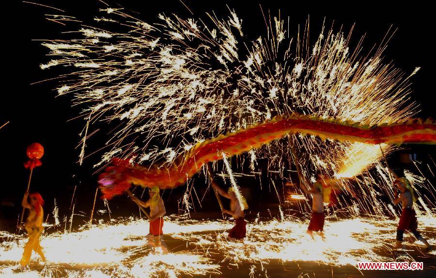 Actors perform dragon dance in firecrackers at the Daguan Park in Kunming, capital of southwest China's Yunnan Province, Feb. 6, 2013. The dance, as a derivative of traditional dragon dance in which performers hold dragon on poles and walk through floods of firecrackers, is a state intangible cultural heritage. (Xinhua/Lin Yiguang)