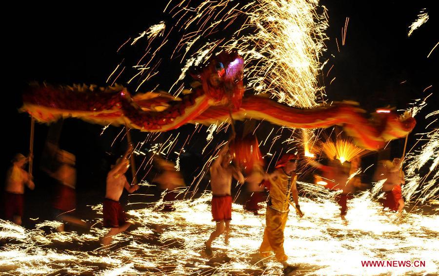 Actors perform dragon dance in firecrackers at the Daguan Park in Kunming, capital of southwest China's Yunnan Province, Feb. 6, 2013. The dance, as a derivative of traditional dragon dance in which performers hold dragon on poles and walk through floods of firecrackers, is a state intangible cultural heritage. (Xinhua/Lin Yiguang)