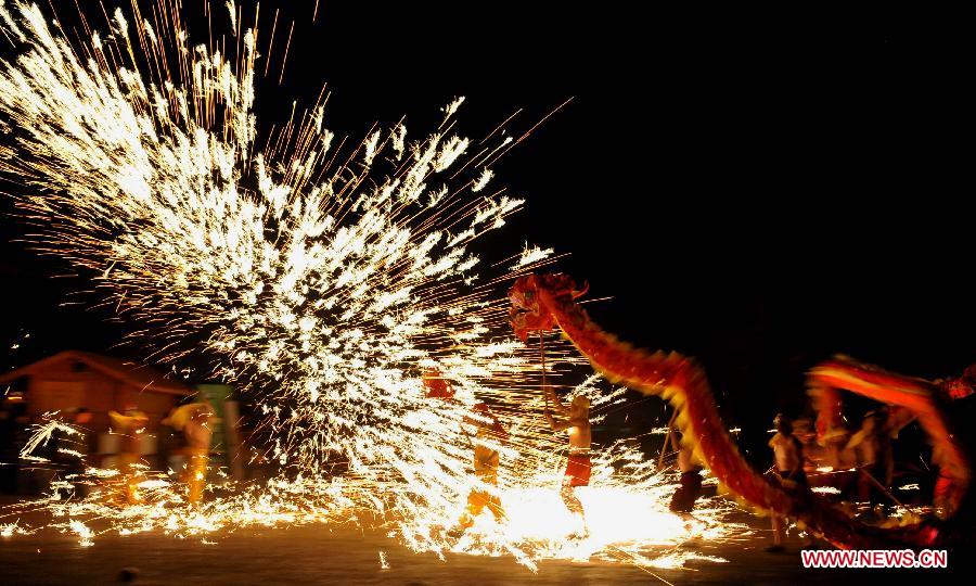 Actors perform dragon dance in firecrackers at the Daguan Park in Kunming, capital of southwest China's Yunnan Province, Feb. 6, 2013. The dance, as a derivative of traditional dragon dance in which performers hold dragon on poles and walk through floods of firecrackers, is a state intangible cultural heritage. (Xinhua/Lin Yiguang)