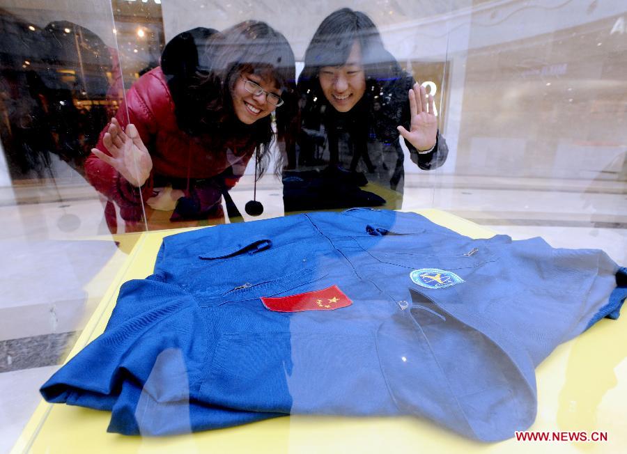 Visitors look at space suits presented on the First Shenyang Aerospace Science Exhibition in Shenyang, capital of northeast China's Liaoning Province, Feb. 7, 2013. Space food, devices, models of Shenzhou spacecraft and China-developped rockets are among the exhibits. (Xinhua/Zhang Wenkui)