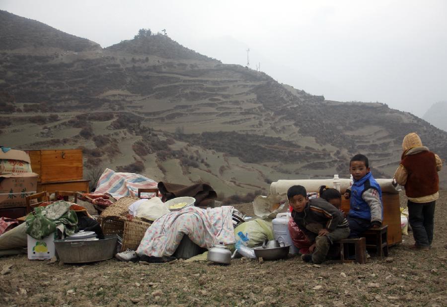 Children sit by life materials saved from a scene of fire in Heiduo Village of Diebu County in northwest China's Gansu Province, Feb. 7, 2013. The fire broke out in Heiduo Village around 8 p.m. and was put out Thursday morning, leaving destruction of 92 homes and no casualties. (Xinhua/Liu Wenchao)