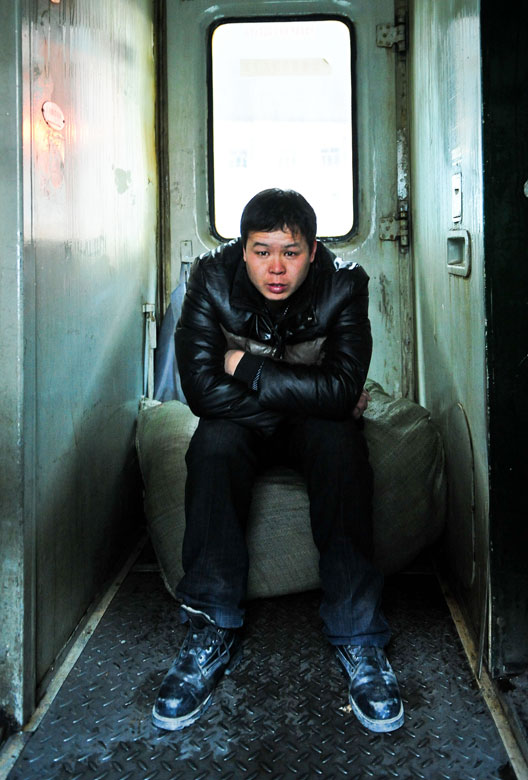 A photo taken on Jan. 26 shows a man sitting on his luggage on the junction section of a passenger train. Since the beginning of Spring Festival travel rush last month, many passengers have to suffer a long journey without a seat due to train ticket shortage. (Xinhua/Zhang Chaoqun)