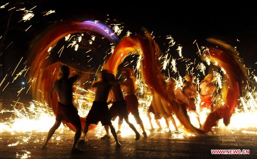 Actors perform dragon dance in firecrackers at the Daguan Park in Kunming, capital of southwest China's Yunnan Province, Feb. 6, 2013. The dance, as a derivative of traditional dragon dance in which performers hold dragon on poles and walk through floods of firecrackers, is a state intangible cultural heritage. (Xinhua/Lin Yiguang)