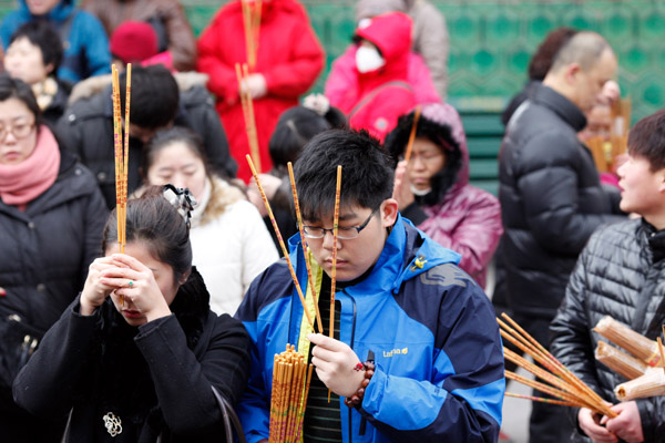 People pray for good fortune as they hold burning incense on the first day of the Chinese Lunar New Year at Yonghegong Lama Temple in Beijing Feb 10, 2013. (Photo/chinadaily.com.cn)