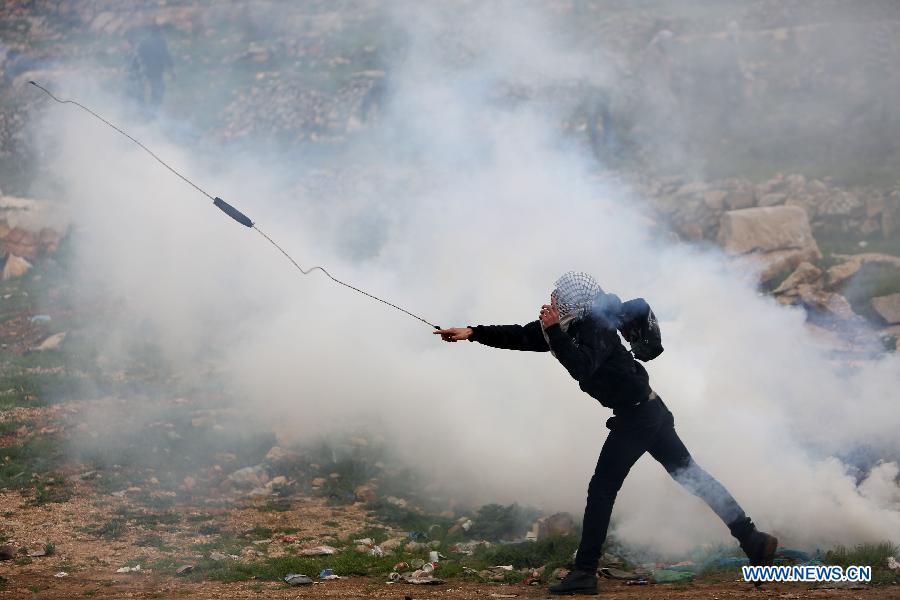 A Palestinian protestor throws stones towards Israeli troops outside Ofer Prison near the West Bank city of Ramallah on Feb.12, 2013. Five protestors supporting Palestinian prisoners were reported injured during the clashes. (Xinhua/Fadi Arouri) 