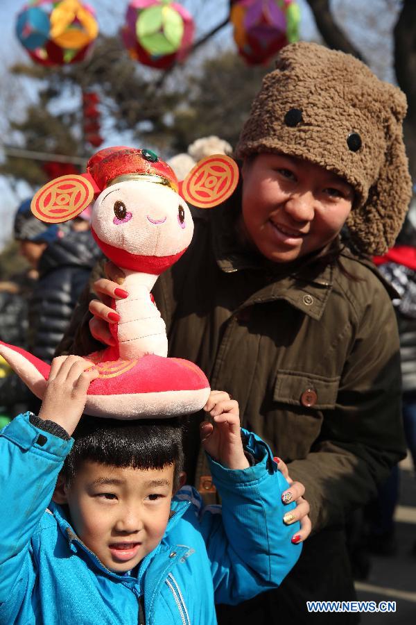 Visitors play with a snake-shaped plush toy at a temple fair held to celebrate the Spring Festival, or the Chinese Lunar New Year, in Beijing, capital of China, Feb. 12, 2013. (Xinhua/Chen Xiaogen)