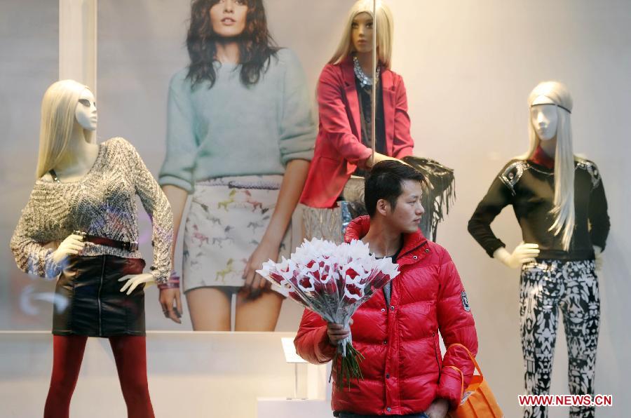 A man holding a bunch of roses is seen on a road in Changsha, capital of central China's Hunan Province, Feb. 14, 2013. Various ornaments were decorated to celebrate the Valentine's day in Changsha. [Xinhua/Li Ga]