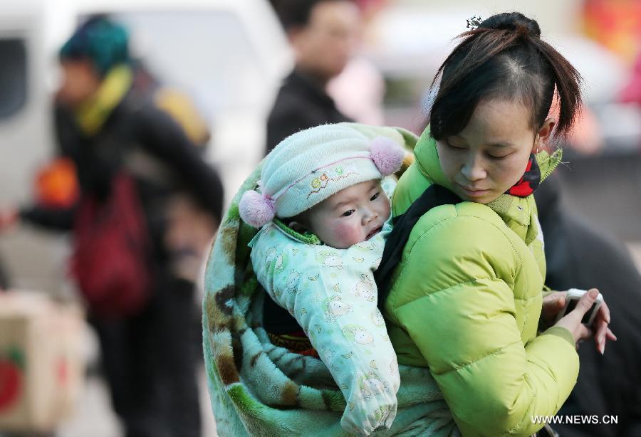 A woman carries her child on the back at the square of Guilin Railway Station in Guilin, southwest China's Guangxi Zhuang Autonomous Region, Feb. 15, 2013. Many children travel with their families during the Spring Festival travel rush. The Spring Festival holiday came to an end on Friday. (Xinhua/He Pingjiang) 