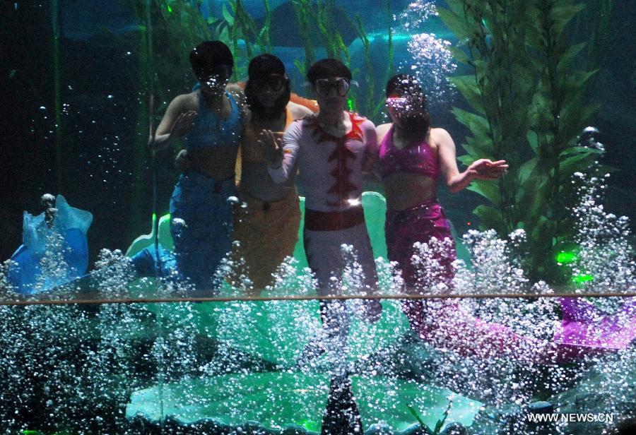 Performers wave to spectators in water at Qingdao Underwater World in Qingdao, east China's Shandong Province, Feb. 15, 2013. During the Spring Festival holidays, an underwater performance telling the story of a mermaid and a prince attracted many visitors in Qingdao. Visual, audio and electronical technologies were applied to the performance. (Xinhua/Li Ziheng)