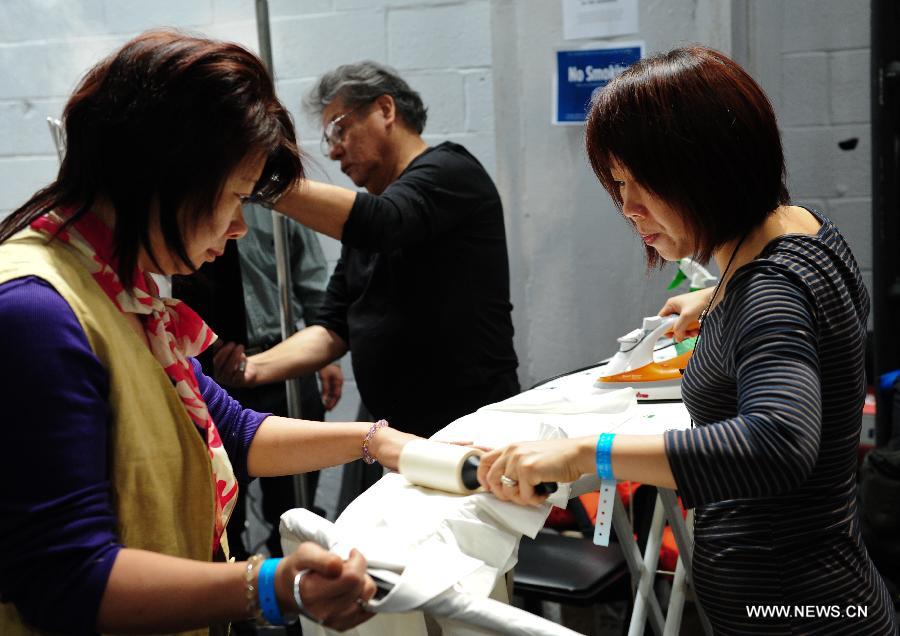 Staff members iron a shirt at the backstage before the presentation of Ralph Lauren 2013 Fall collections of the Mercedes-Benz Fashion Week in New York, Feb. 14, 2013. (Xinhua/Deng Jian)