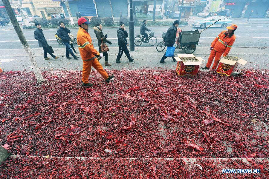 Sanitation workers clean firecracker scraps in front of a bank in Hangzhou, capital of east China's Zhejiang Province, Feb. 16, 2013. Saturday marks the first working day after the one-week Spring Festival break which started on Feb. 9. Setting off firecrackers on this day is a traditional custom for businessmen to pray for a booming year. (Xinhua/Li Zhong)