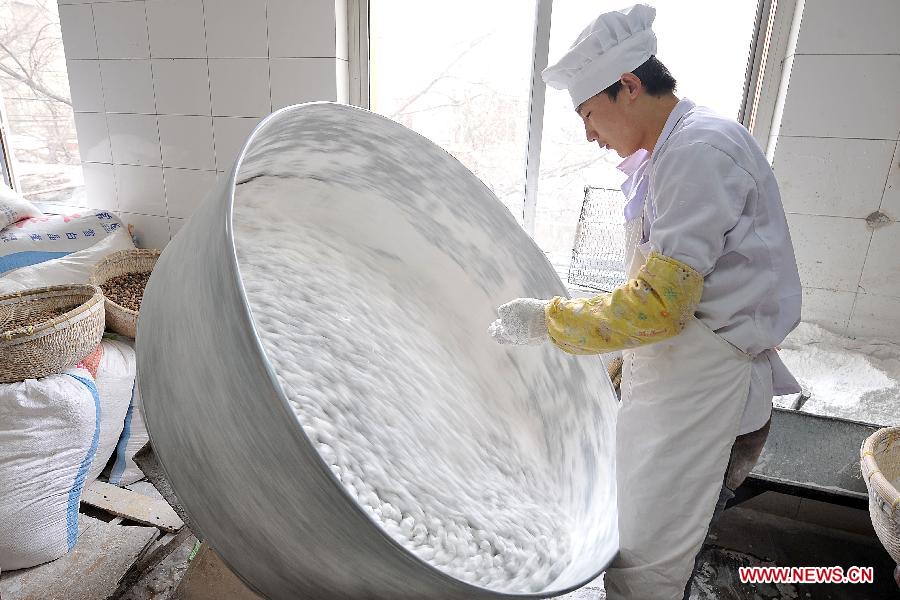 A cook makes Yuanxiao, glutinous rice flour dumpling with sweetened stuffing, at a food shop in Taiyuan, capital of north China's Shanxi Province, Feb. 16, 2013. Yuanxiao is a traditional festive food for the Lantern Festival, which falls on Feb. 24 this year. (Xinhua/Zhan Yan)  