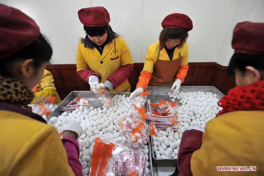 Staff members pack Yuanxiao, glutinous rice flour dumpling with sweetened stuffing, at a food shop in Taiyuan, capital of north China's Shanxi Province, Feb. 16, 2013. Yuanxiao is a traditional festive food for the Lantern Festival, which falls on Feb. 24 this year. (Xinhua/Zhan Yan)  