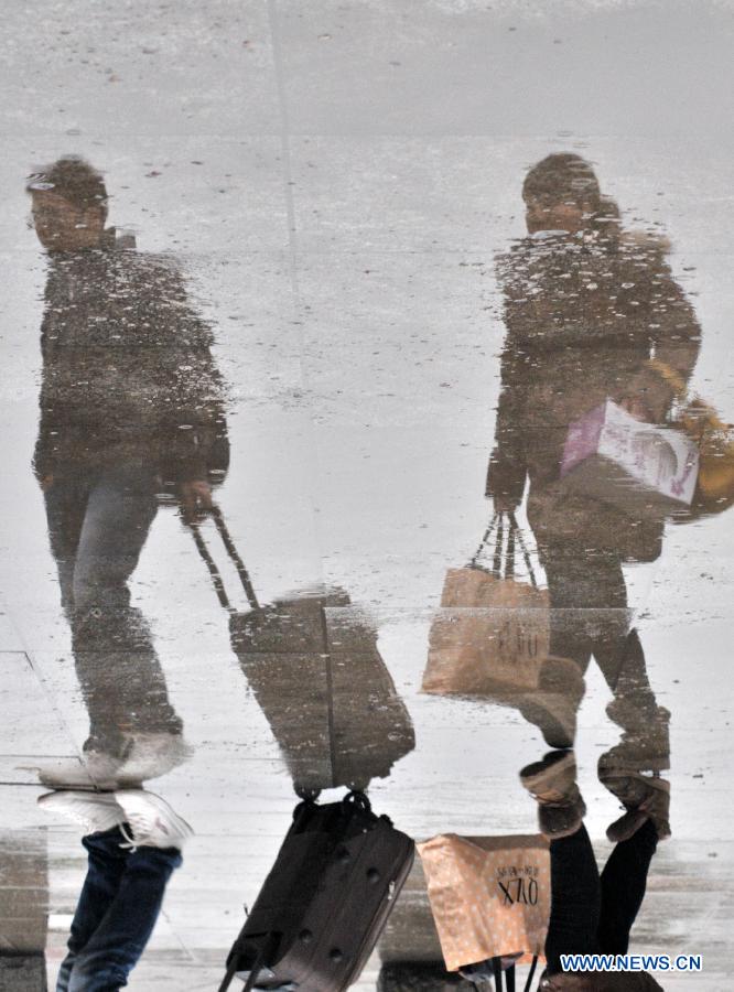 Passengers are seen reflected on the ground as they walk in the city railway station in Jiujiang, east China's Jiangxi Province, Feb. 17, 2013. China saw a travel rush after the week-long Spring Festival holiday as millions of workers move to big cities for better working opportunities. (Xinhua/Hu Guolin)