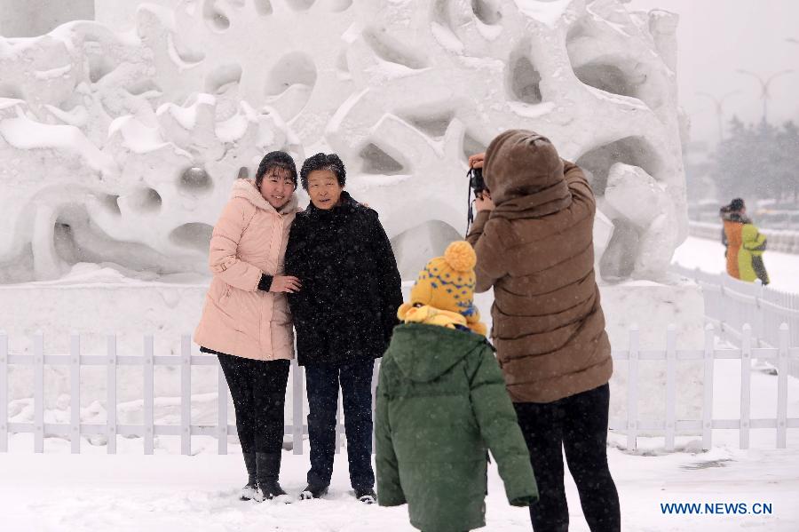 People pose for photos with a snow sculpture in Changchun, capital of northeast China's Jilin Province, Feb. 17, 2013. Snow hit the province on Sunday. (Xinhua/Lin Hong) 