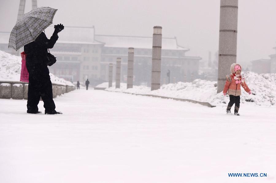 A man takes photo for his daughter in snow in Changchun, capital of northeast China's Jilin Province, Feb. 17, 2013. Snow hit the province on Sunday. (Xinhua/Lin Hong) 
