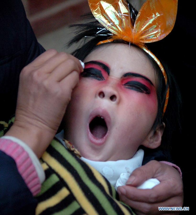 File photo taken on Feb. 11, 2006 shows a young folk artist doing facial makeup for Shehuo performances in Xidian Village of Jiuxian Town, Songxian County, central China's Henan Province. (Xinhua/Wang Song)