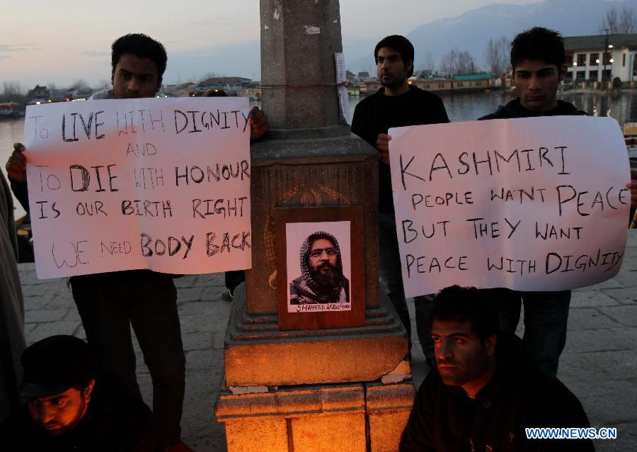 Students hold placards near the photograph of 2001 Indian parliament attack convict Mohammed Afzal Guru during a candle light protest demanding Guru's body back in Srinagar, summer capital of Indian-controlled Kashmir, Feb. 17, 2013. (Xinhua/Javed Dar)