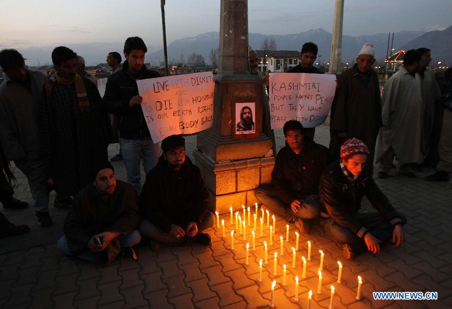 Students hold placards near the photograph of 2001 Indian parliament attack convict Mohammed Afzal Guru during a candle light protest demanding Guru's body back in Srinagar, summer capital of Indian-controlled Kashmir, Feb. 17, 2013. (Xinhua/Javed Dar)