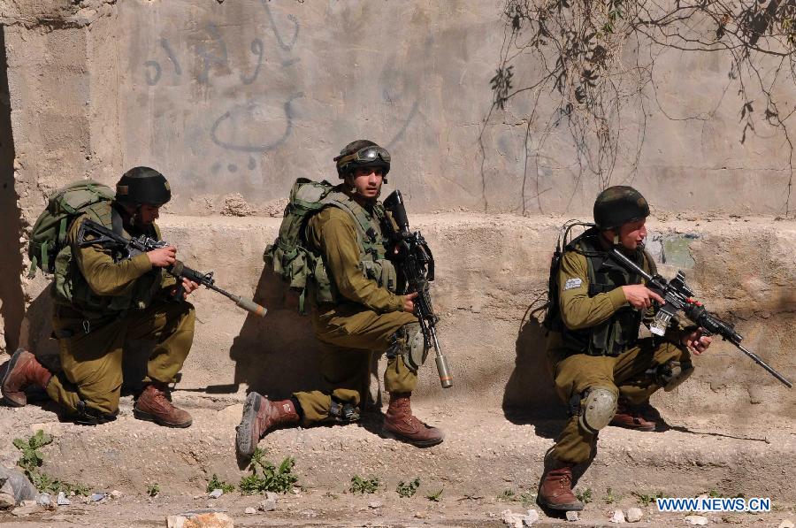 Israeli soldiers take position during clashes with Palestinian protesters following a demonstration supporting the Palestinian prisoners in Israeli jails, in al-Arrub refugee camp, north of the West Bank city of Hebron, on Feb. 18, 2013. (Xinhua/Mamoun Wazwaz) 