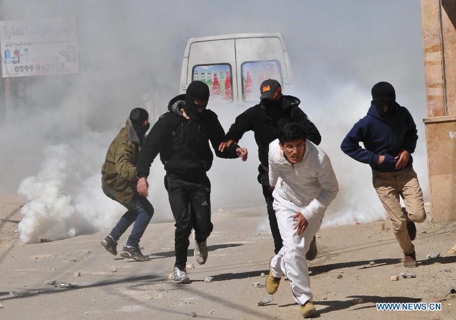 Palestinian protesters take cover from tear gas fired by Israeli soldiers during clashes erupted following a demonstration supporting the Palestinian prisoners in Israeli jails, in al-Arrub refugee camp, north of the West Bank city of Hebron, on Feb. 18, 2013. (Xinhua/Mamoun Wazwaz)