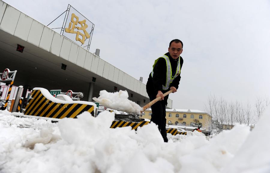 A staff member cleans the snow at an entrance of an intercity express way in Hefei, capital of east China's Anhui Province, Feb. 19, 2013. Snowstorm hit multiple places in Anhui Tuesday morning, disturbing the local traffic. (Xinhua/Liu Junxi)
