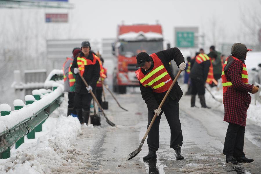 Staff members clean the snow at an entrance of an intercity express way in Hefei, capital of east China's Anhui Province, Feb. 19, 2013. Snowstorm hit multiple places in Anhui Tuesday morning, disturbing the local traffic. (Xinhua/Du Yu) 