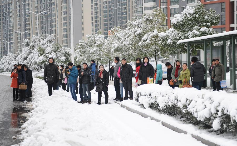 People wait at a snow-covered bus stop in Hefei, capital of east China's Anhui Province, Feb. 19, 2013. Snowstorm hit multiple places in Anhui Tuesday morning, disturbing the local traffic. (Xinhua/Du Yu)