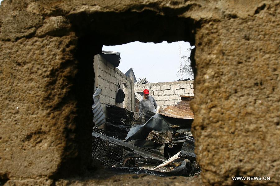 A man looks for reuseable materials at his charred home after a fire hit a residential area in Valenzuela City, the Philippines, Feb. 19, 2013. Around 500 houses were razed in the fire, leaving 2,000 residents homeless. (Xinhua/Rouelle Umali) 