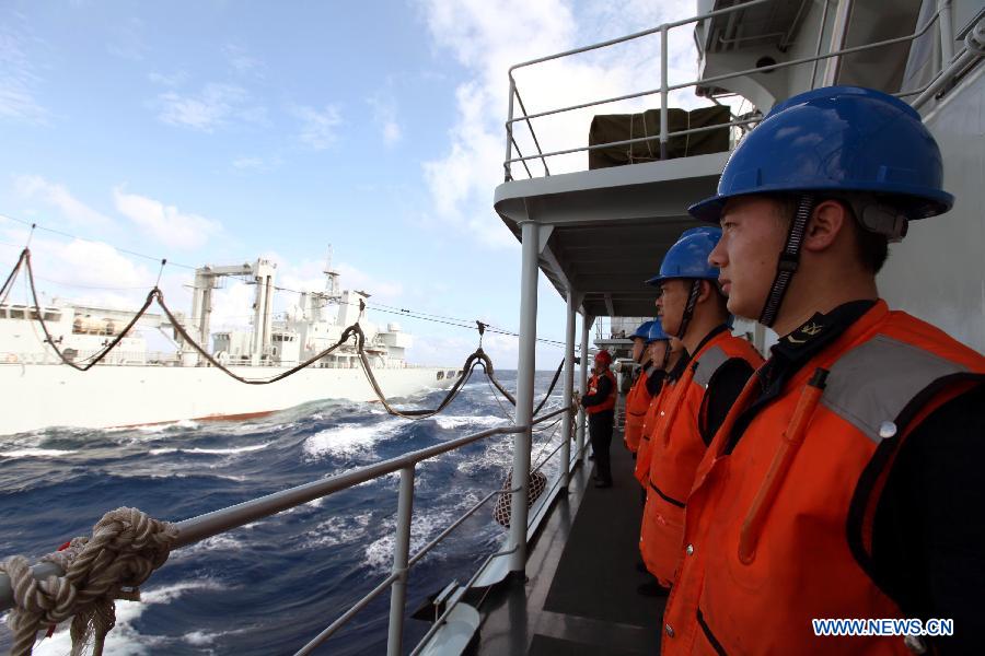 Crew members onboard missile destroyer Harbin stand as the supply ship Weishanhu tranport fuel and other materials at South China Sea, Feb. 20, 2013. The supply ship Weishanhu reinforced the missile destroyer Harbin and the frigate Mianyang on Wednesday with fuel, fresh water and other materials. The 14th naval squad, sent by the Chinese People's Liberation Army (PLA) Navy, departed Saturday from China to the Gulf of Aden and Somali waters for escort missions. The fleet comprises three ships -- the missile destroyer Harbin, the frigate Mianyang and the supply ship Weishanhu -- carrying two helicopters and a 730-strong troop. (Xinhua/Rao Rao)