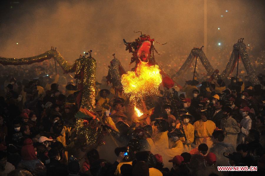 People perform dragon dance in firecrackers in Binyang County of south China's Guangxi Zhuang Autonomous Region, Feb. 20, 2013. The Binyang-style dragon dance is a derivative of traditional dragon dance in which performers hold dragon on poles and walk through floods of firecrackers. The dance, dating back to over 1,000 years ago, was listed as a state intangible cultural heritage in 2008. (Xinhua/Huang Xiaobang) 