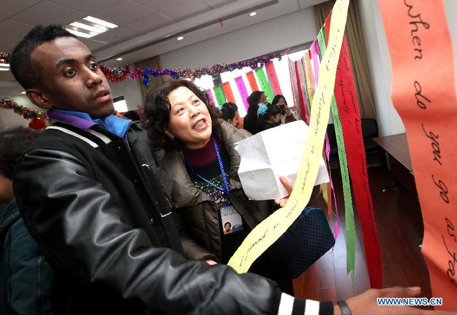 Ma Liang (1st L) from Madagascar takes part in a puzzle game at a community in Shanghai, east China, Feb. 21, 2013. Some foreign students on Thursday came to a community in Shanghai to feel the atmosphere of the upcoming Lantern Festival. (Xinhua/Chen Fei) 