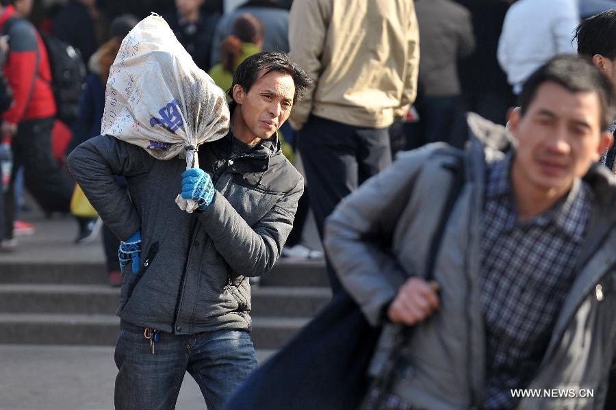 Passengers are seen carring their luggage on the square of the train station in Taiyuan, capital of north China's Shanxi Province, Feb. 21, 2013. Many people started their trips back to their working places after the Spring Festival holiday in recent days. (Xinhua/Zhan Yan)