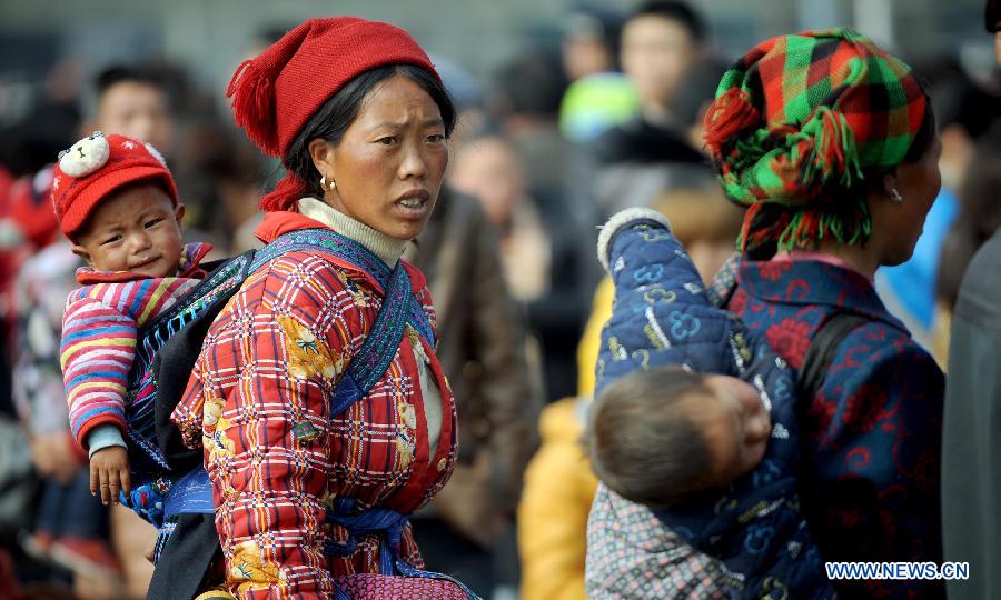 Passengers carry their children on the back as the wait at the railway station in Chengdu, capital of southwest China's Sichuan Province, Feb. 22, 2013. As the number of travellers rises before the Lantern Festival, many children went back with their parents back to the workplaces. (Xinhua/Xue Yubin) 