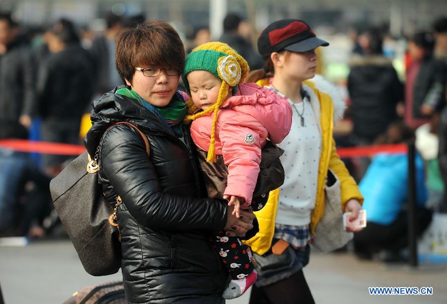 A passenger holds a child in her arms at the railway station in Chengdu, capital of southwest China's Sichuan Province, Feb. 22, 2013. As the number of travellers rises before the Lantern Festival, many children went back with their parents back to the workplaces. (Xinhua/Xue Yubin) 