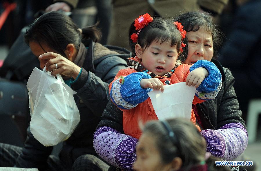 A girl waits with his relative at the railway station in Chengdu, capital of southwest China's Sichuan Province, Feb. 22, 2013. As the number of travellers rises before the Lantern Festival, many children went back with their parents back to the workplaces. (Xinhua/Xue Yubin)